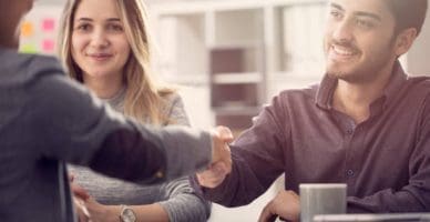 Young couple shaking hands with a female agent